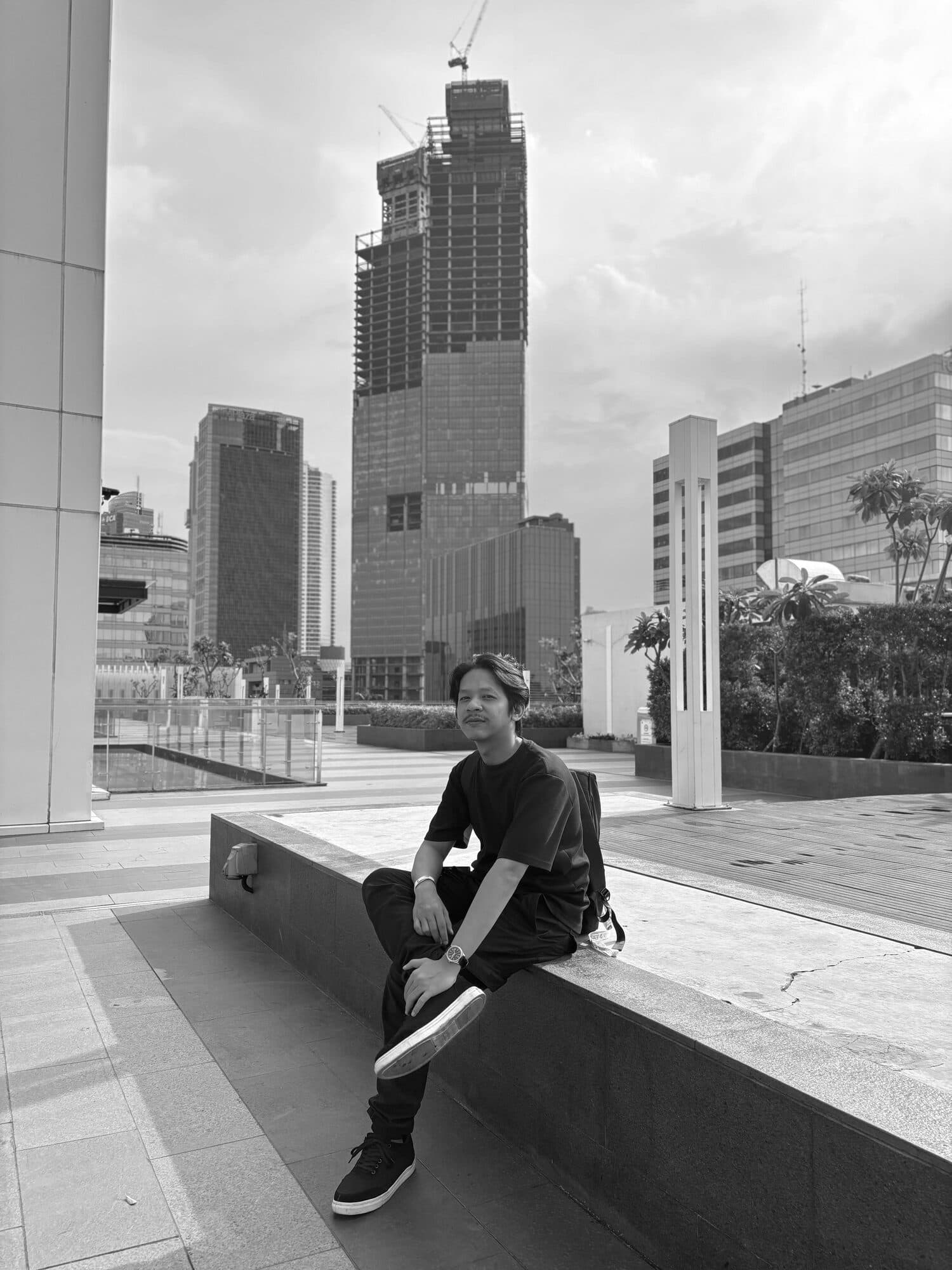 Anugrah Surya Putra sitting on a ledge in the city